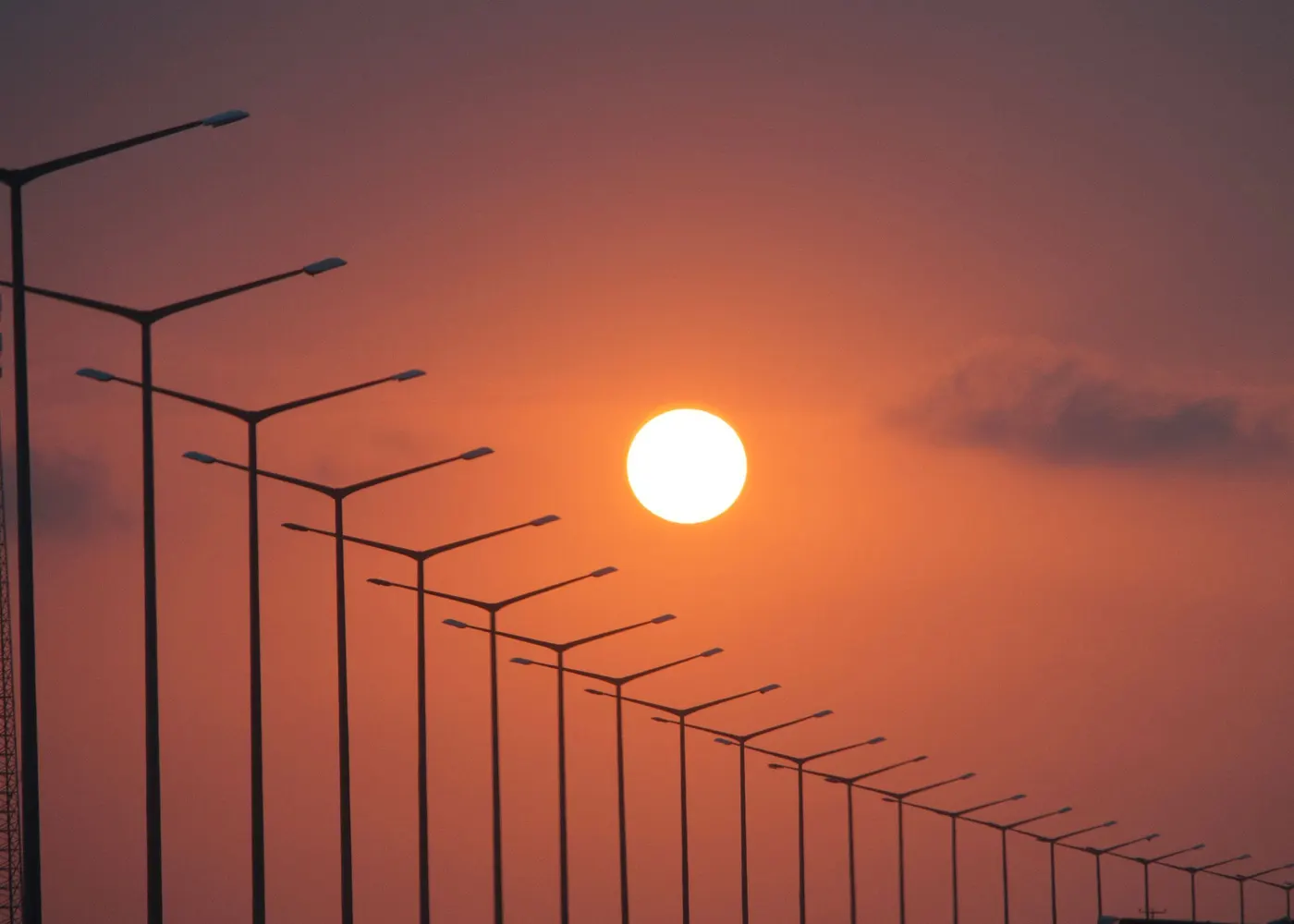 Silhouette of a row of street lights against a sunset sky